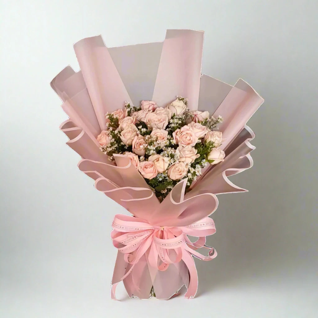 Bouquet of pink roses wrapped in pink paper with a bow on a light gray background