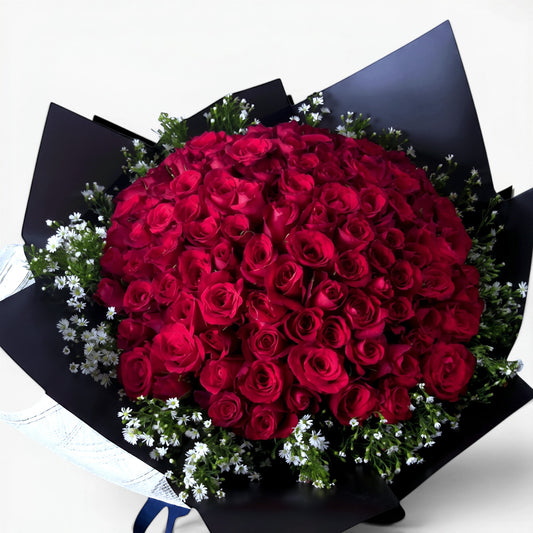 The Flowercart Meadow Fresh bouquet of 100 crimson roses and baby's breath wrapped in elegant black paper.