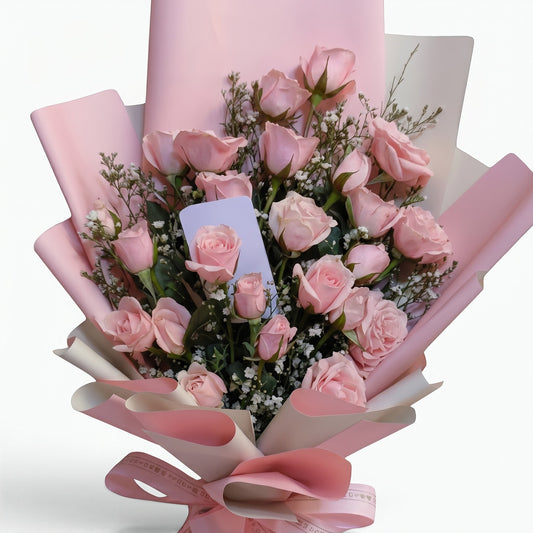 The Flowercart Pink Whisper bouquet featuring 24 fresh pink roses and baby's breath wrapped in elegant pink paper.