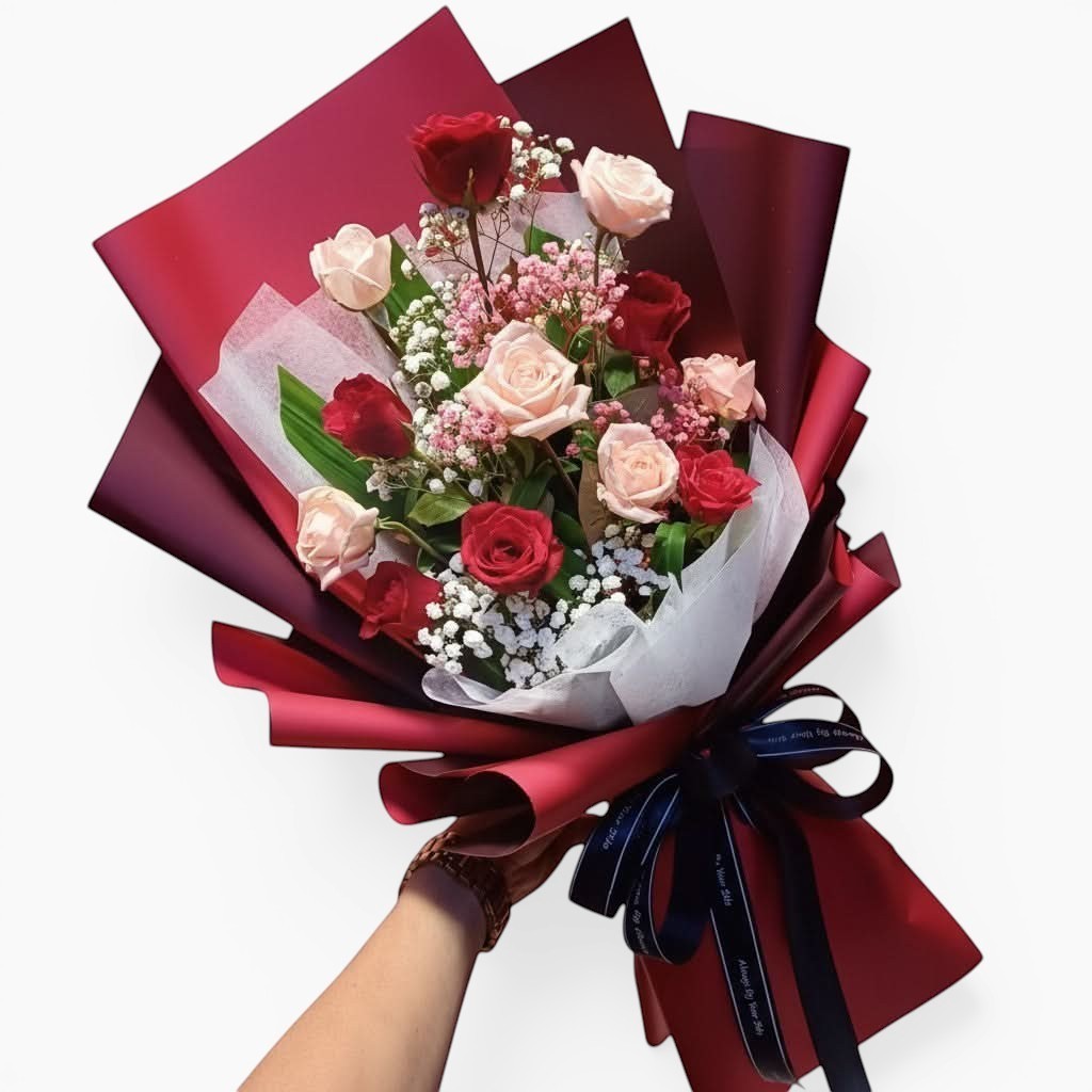 The Flowercart Wendy's Bouquet featuring red and pink roses with baby's breath wrapped in deep red paper with a ribbon.