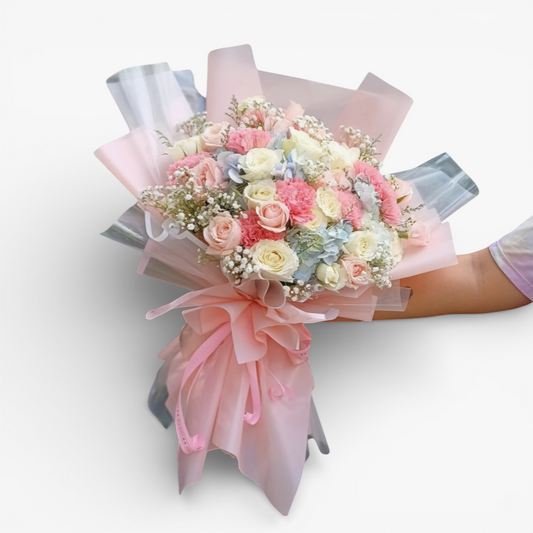 The Flowercart Pastel Dreams bouquet with pink roses, white roses, pink carnations, blue hydrangea, and baby's breath.
