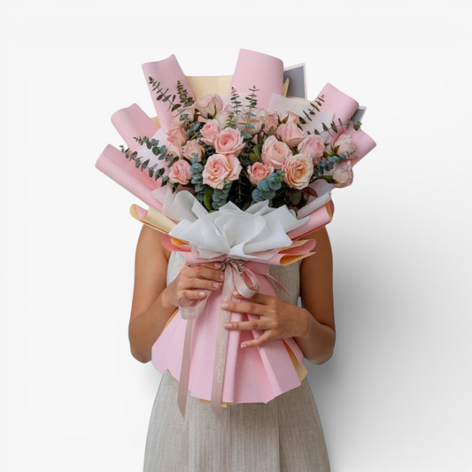 The Flowercart bouquet with 24 soft pink roses and eucalyptus, wrapped in blush paper and tied with a ribbon.