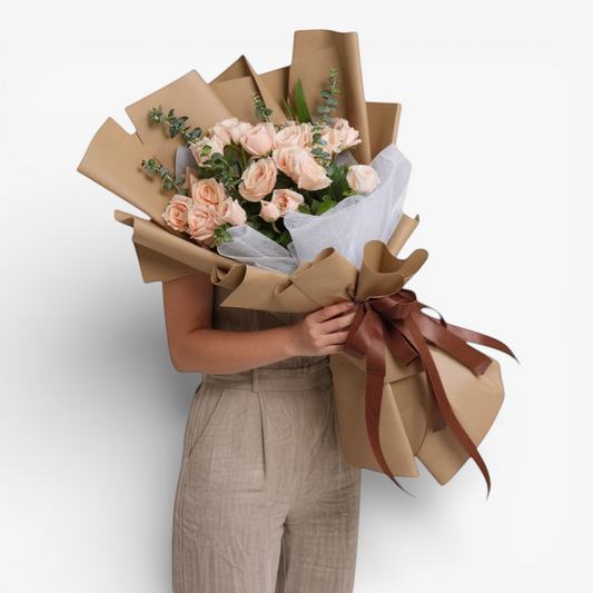 The Flowercart Terra Cotta bouquet features 24 soft pink roses and eucalyptus, wrapped in brown paper with a satin ribbon.