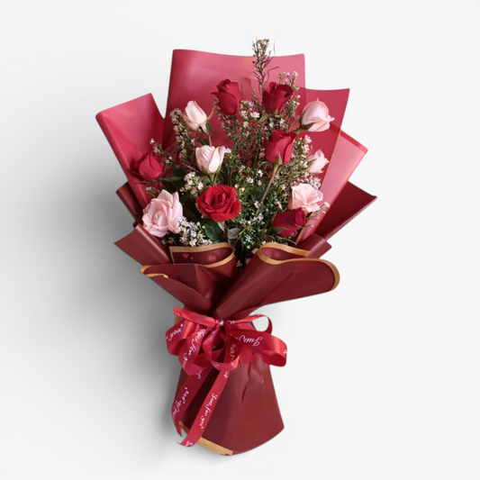 The Flowercart Sweet Heart Bouquet: 12 red and pink roses with baby's breath, wrapped in red paper and ribbon.