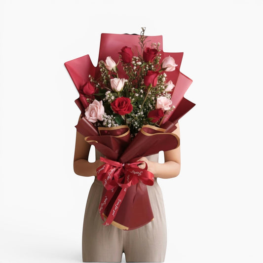 The Flowercart Sweet Heart Bouquet: 12 red and pink roses with baby's breath, wrapped in red paper and ribbon.