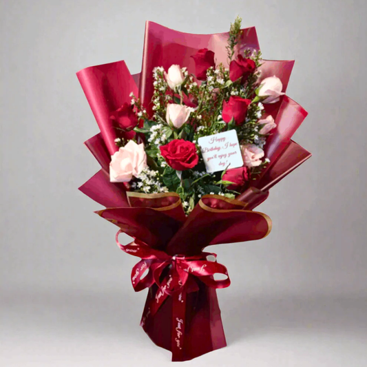 Bouquet of red and pink roses with a card on a gray background