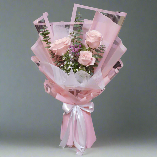Bouquet of pink roses wrapped in white paper with a pink ribbon on a white background