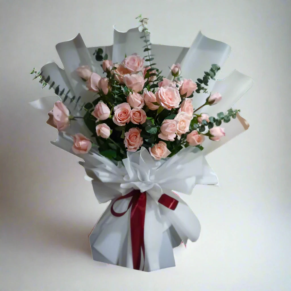 Bouquet of pink roses wrapped in white paper with a red ribbon on a light gray background