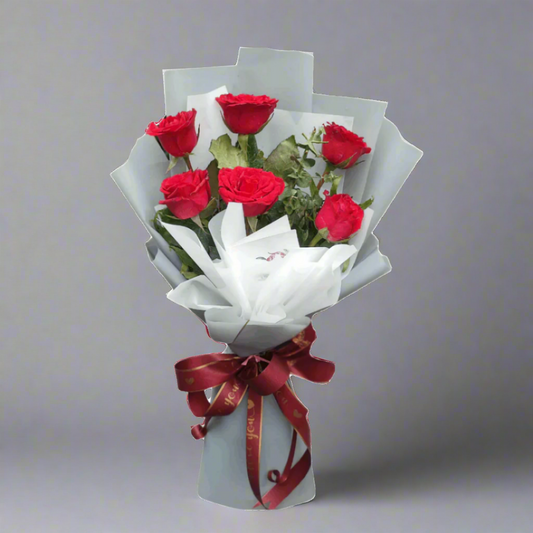 Bouquet of red roses wrapped in gray paper with a red ribbon