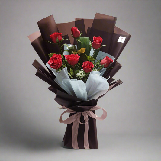 Bouquet of red roses wrapped in brown paper with a pink ribbon on a white background