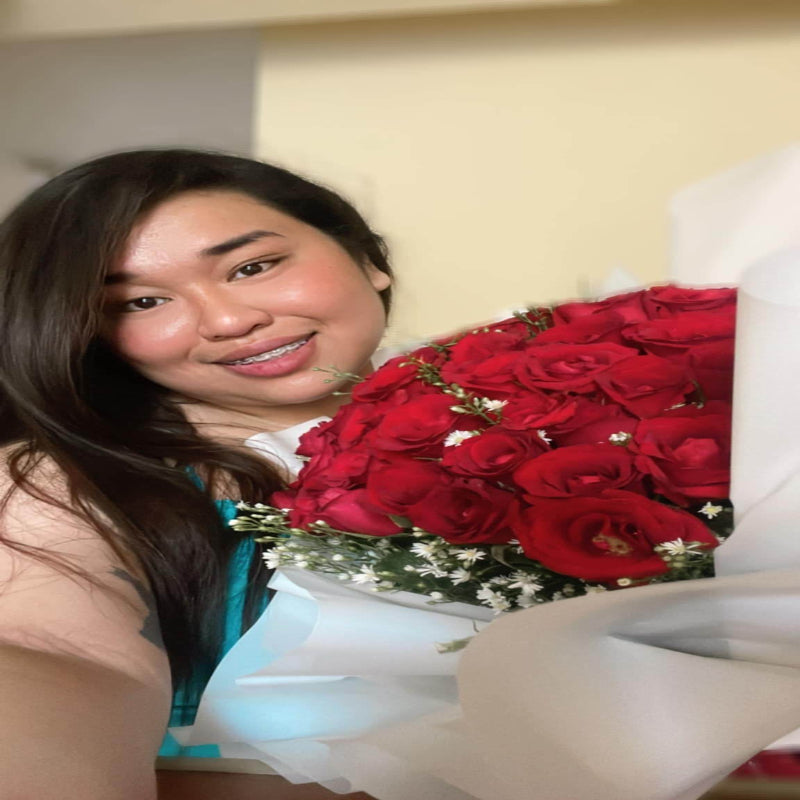 Woman holding a large bouquet of red roses indoors