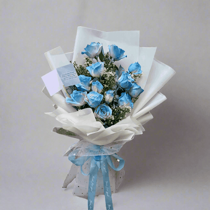 Bouquet of blue roses with white paper wrap and blue ribbon, branded 'The Flowercart'.