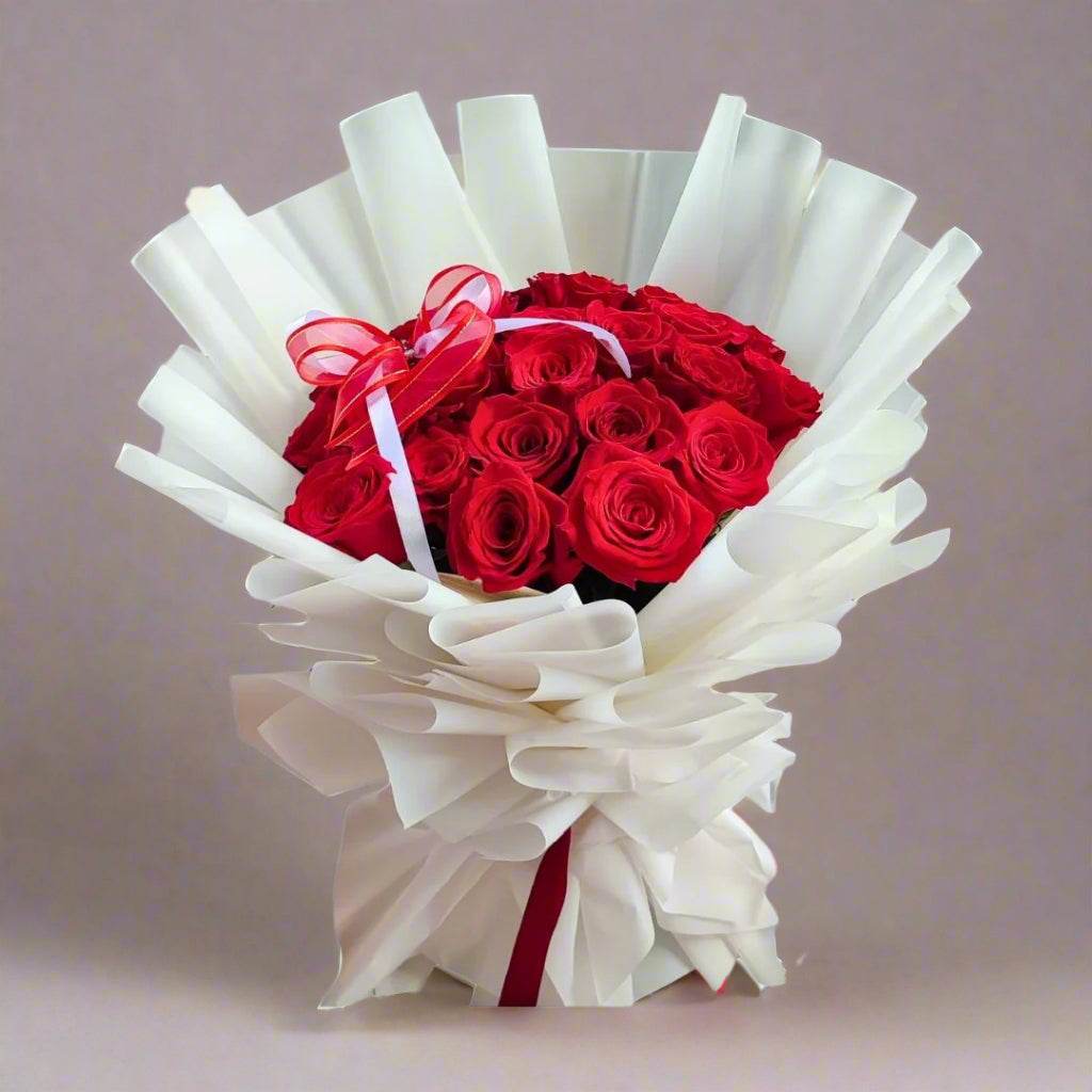 Bouquet of red roses wrapped in white paper with a red ribbon on a white background