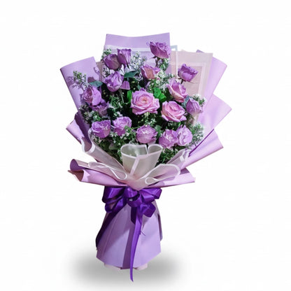 Bouquet of purple and pink flowers wrapped in purple paper with a bow on a white background