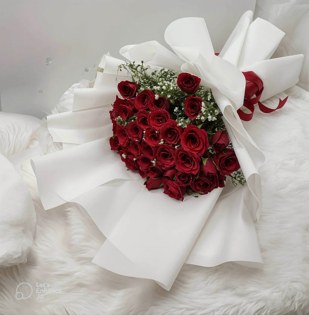 Bouquet of red roses shaped like a heart with white ribbons on a white background