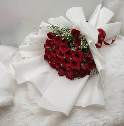 Bouquet of red roses shaped like a heart with white ribbons on a white background