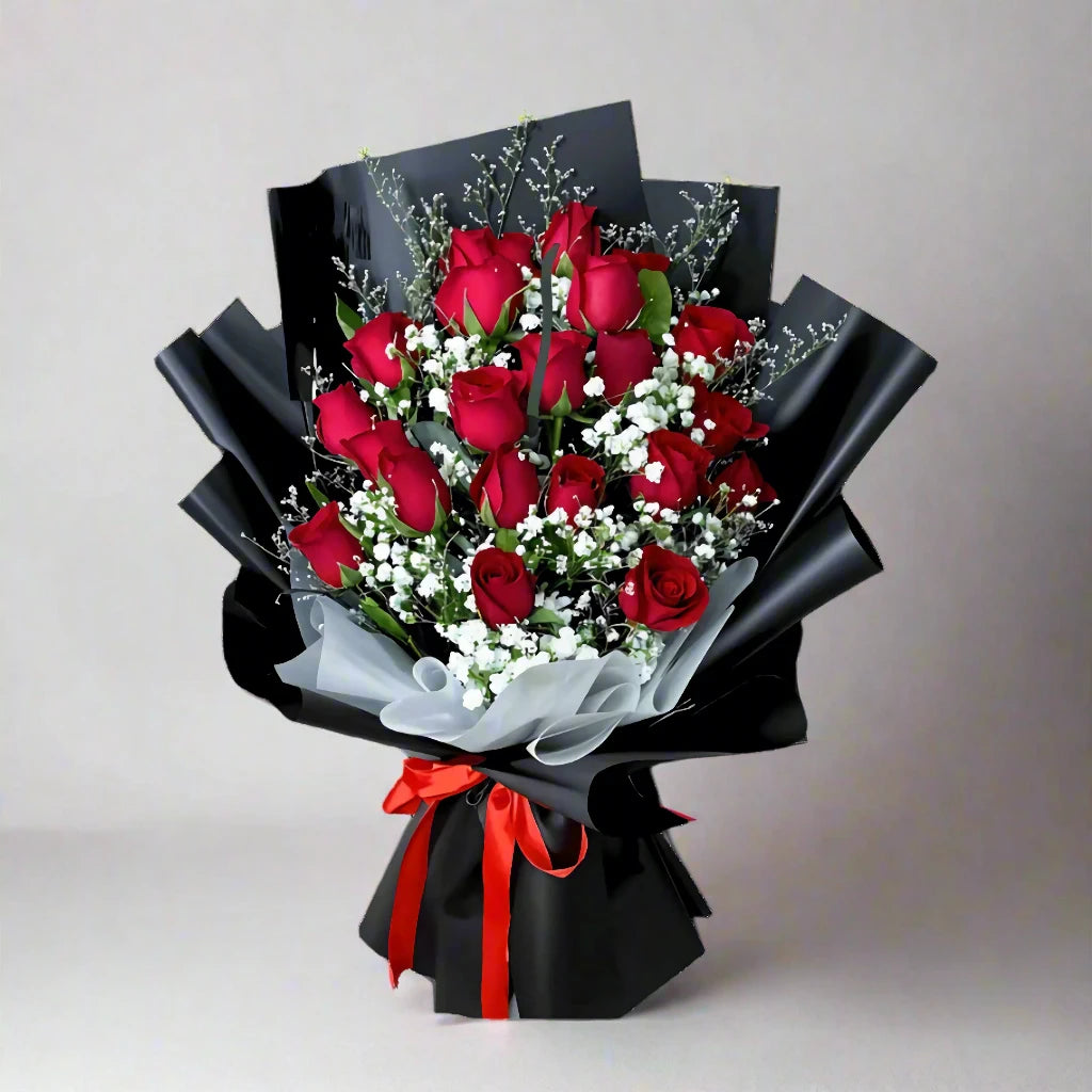 Bouquet of red roses with black wrap and red ribbon on a light gray background