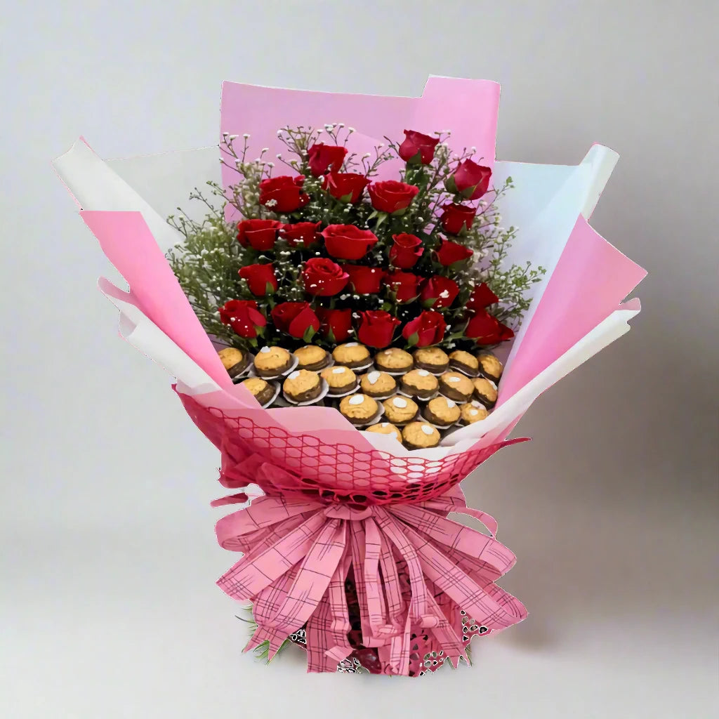 Bouquet of red roses with a pink ribbon and small chocolate cupcakes on a light gray background