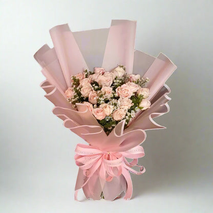 Bouquet of pink roses wrapped in pink paper with a bow on a light gray background