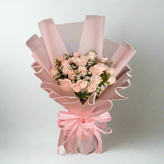 Bouquet of pink roses wrapped in pink paper with a bow on a light gray background