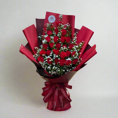 Bouquet of red roses wrapped in red paper on a light background