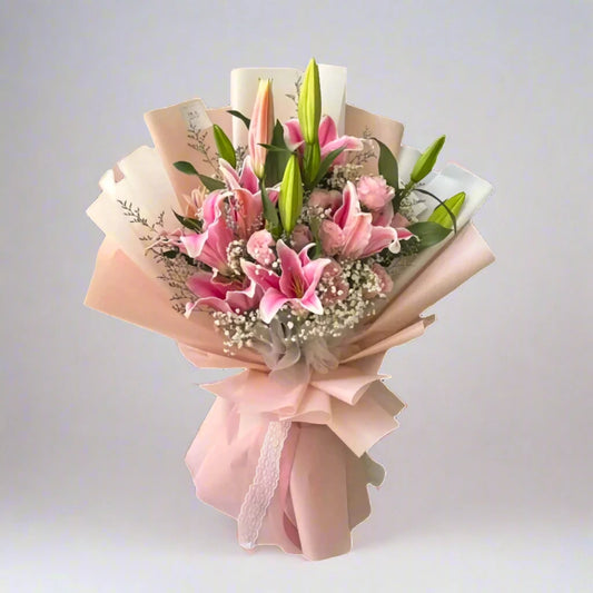 Bouquet of pink lilies wrapped in pink paper on a light gray background