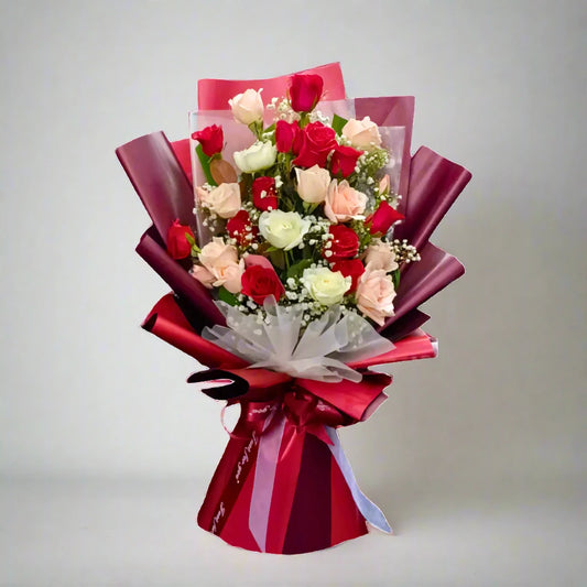 Bouquet of red, pink, and white roses with a red ribbon on a gray background