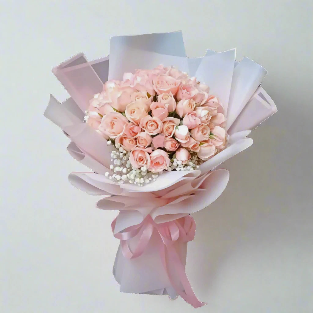 Bouquet of pink roses wrapped in white paper with a pink bow on a light gray background