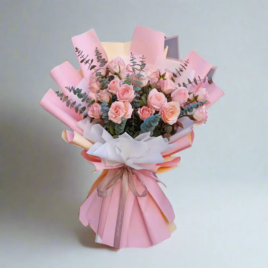 Bouquet of pink flowers wrapped in pink paper on a light gray background