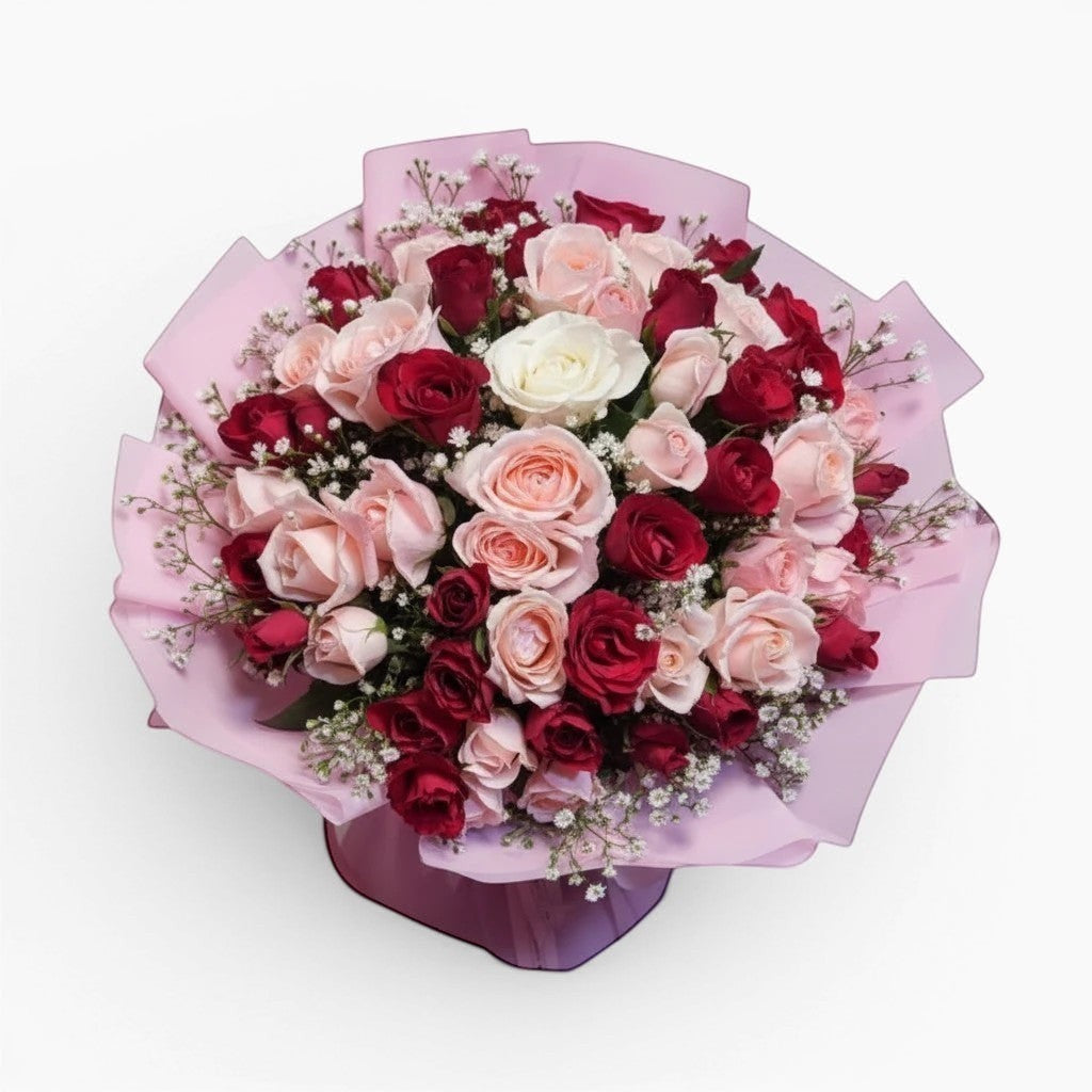 The Flowercart 100 stalk bouquet of mixed red and pink roses with baby's breath in light pink wrapping paper.