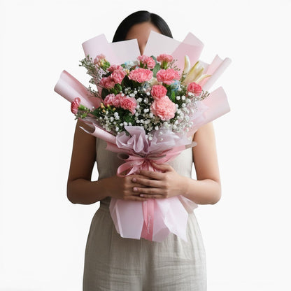 The Flowercart Berry Blush bouquet featuring pink carnations and baby's breath wrapped in soft pink paper.