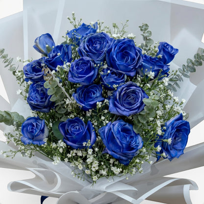 The Flowercart Sapphire Devotion bouquet featuring 16 vibrant blue roses with baby's breath and fresh eucalyptus.