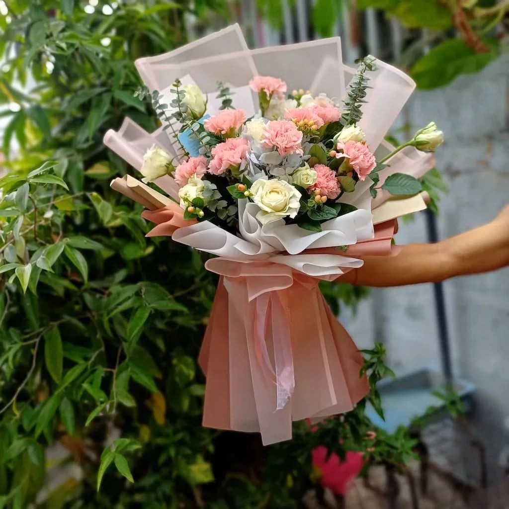 The Flowercart Carnation Carnival bouquet with pink carnations, white roses, blue hydrangeas, and fresh eucalyptus.