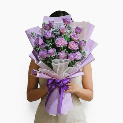 The Flowercart Save the Date bouquet featuring 12 lavender roses wrapped in elegant purple paper held by a person.