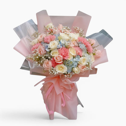 The Flowercart Pastel Dreams bouquet featuring pink and white roses, carnations, blue hydrangea, and baby's breath.