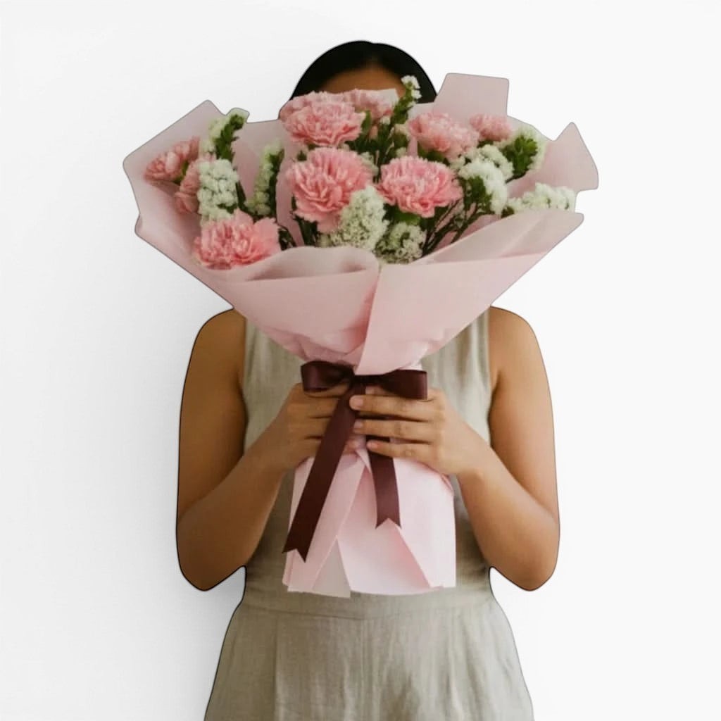 The Flowercart Divine Radiance bouquet of pink carnations and white statice wrapped in pastel pink paper.