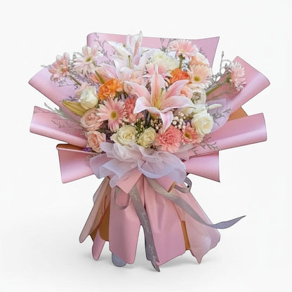 The Flowercart Enchanté Bloom bouquet with pink lilies, roses, gerberas, and carnations wrapped in pink paper.
