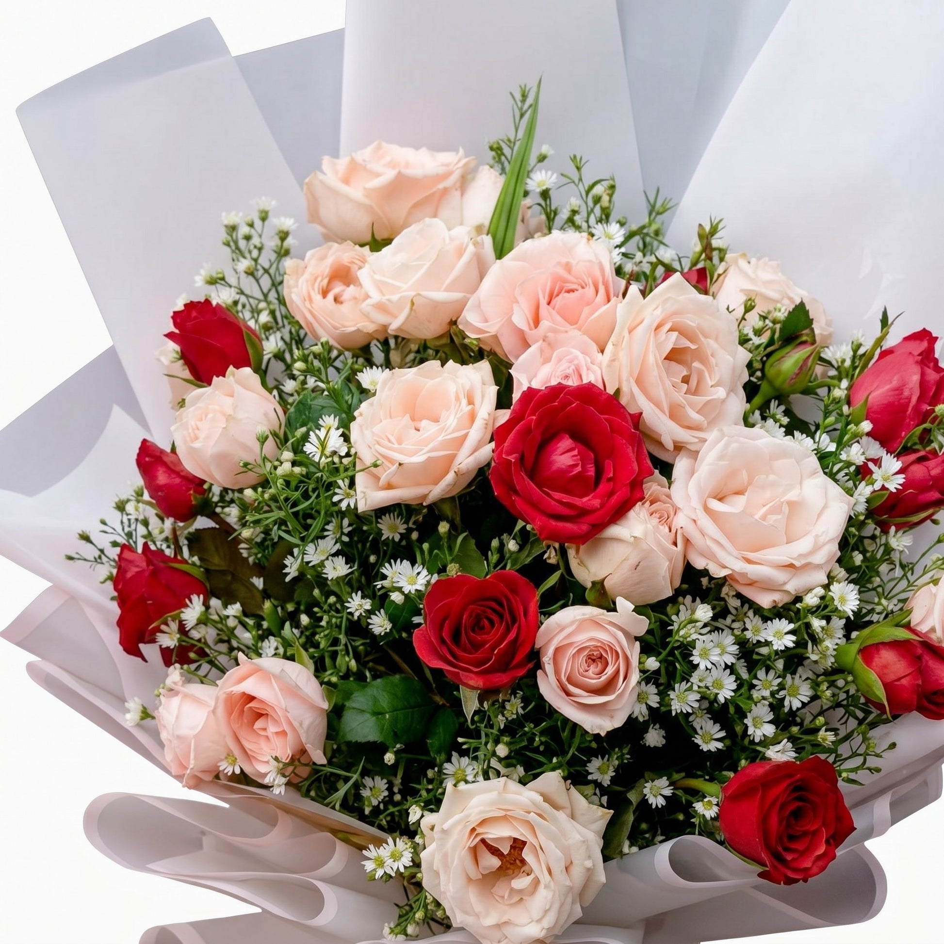 The Flowercart Blushing Harmony bouquet featuring 24 pink and red roses wrapped in white paper with baby's breath.