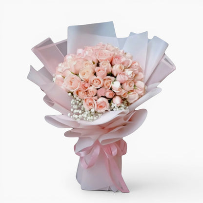 The Flowercart Mardi Gras bouquet featuring 50 premium pink roses and baby's breath wrapped in pink and white paper.