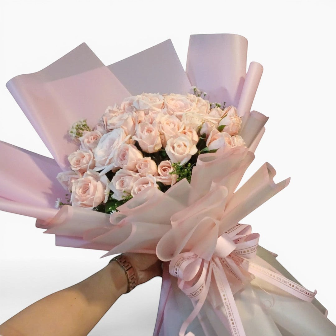 The Flowercart Mardi Gras bouquet featuring 50 premium pink roses and baby's breath in soft pink and white wrapping.
