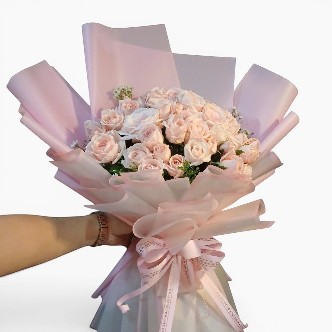 The Flowercart Mardi Gras bouquet featuring 50 premium pink roses and baby's breath wrapped in pink and white paper.