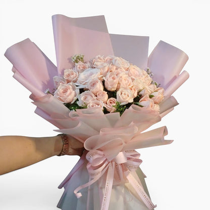 The Flowercart Mardi Gras bouquet featuring 50 premium pink roses and baby's breath wrapped in pink and white paper.
