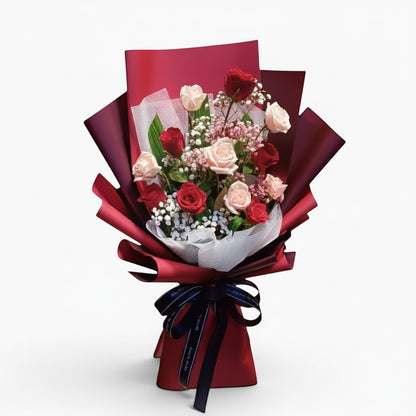 The Flowercart Wendy's Bouquet featuring red and pink roses with baby's breath in elegant dark red wrapping.