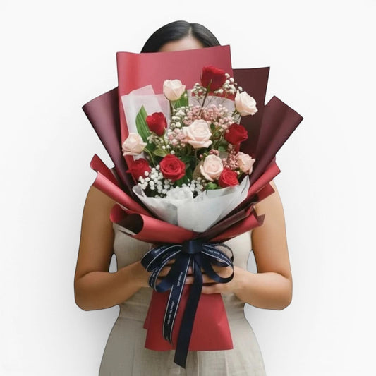 The Flowercart Wendy's Bouquet featuring red and pink roses with baby's breath wrapped in elegant dark red paper.