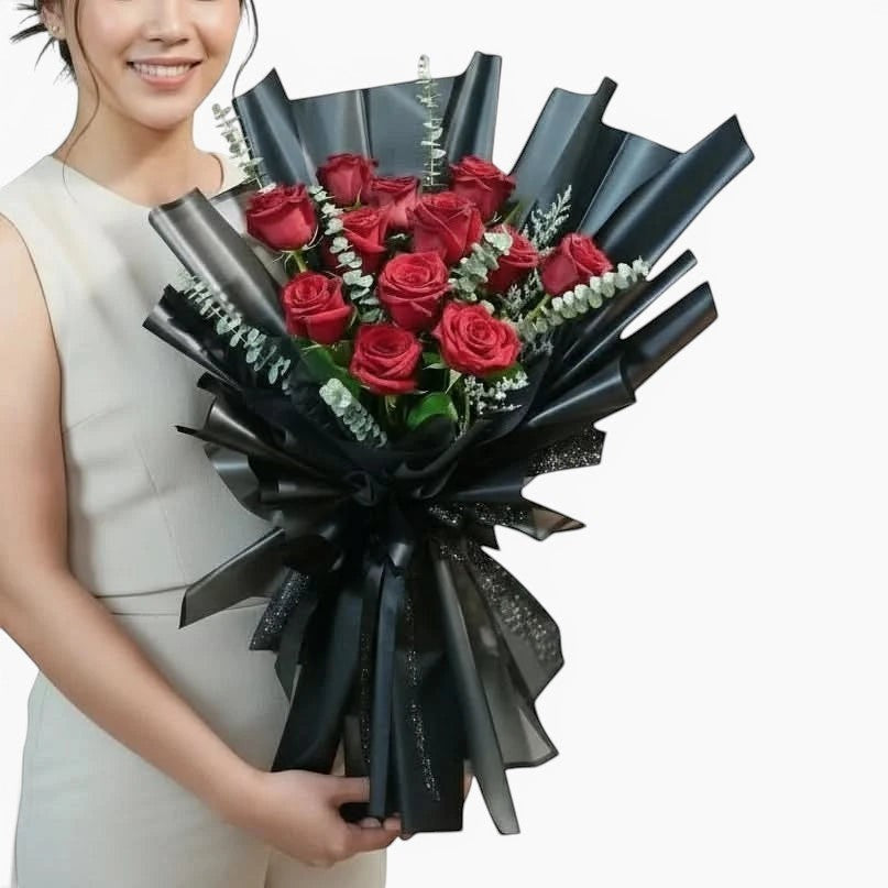 The Flowercart Maison Fleur bouquet featuring 12 red Ecuadorian roses and eucalyptus wrapped in elegant black paper.