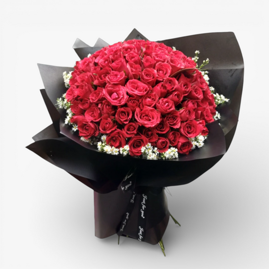The Flowercart's Meadow Fresh bouquet: 100 crimson roses with baby's breath, wrapped in black paper.