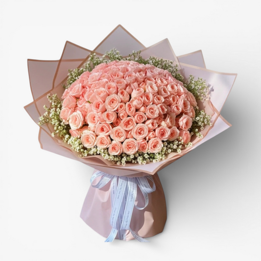 The Flowercart 199 baby pink roses bouquet with delicate white filler flowers and light pink wrapping, tied with a white ribbon.