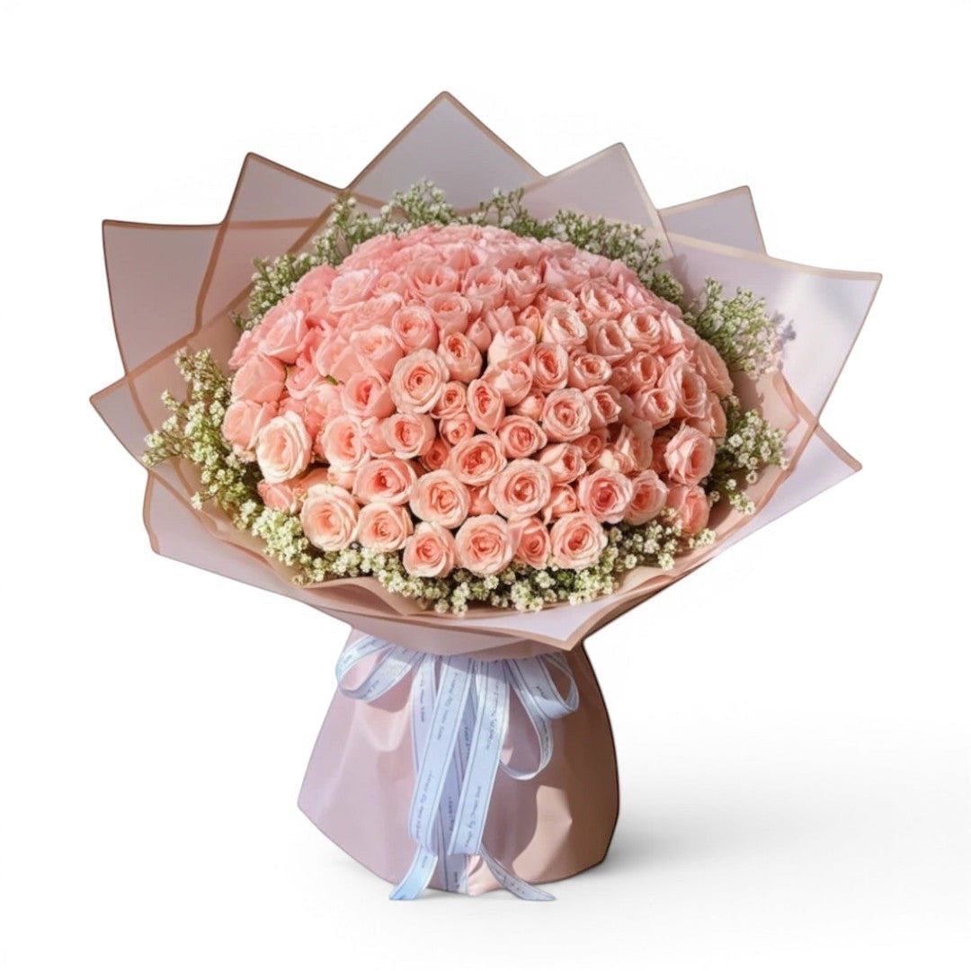 The Flowercart 199 baby pink roses bouquet with delicate white filler flowers and light pink wrapping, tied with a white ribbon.