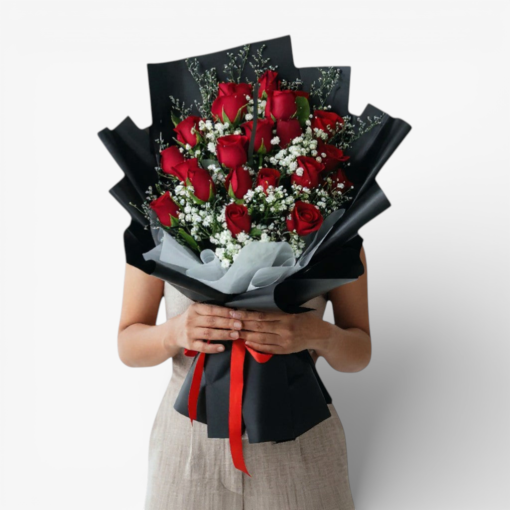 The Flowercart Luxe Noir bouquet: 24 red roses with white fillers, wrapped in black paper and tied with a red ribbon.