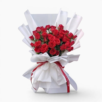The Flowercart 36 red roses bouquet, elegantly wrapped in white paper with a red ribbon, perfect for anniversaries and romantic occasions.
